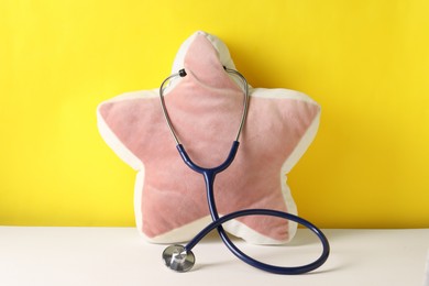 Star shaped pillow with stethoscope on color background