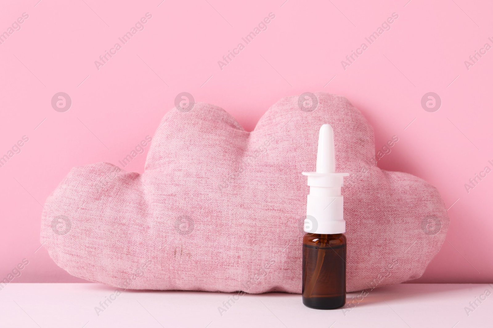 Photo of Cloud shaped pillow and nasal spray on color background