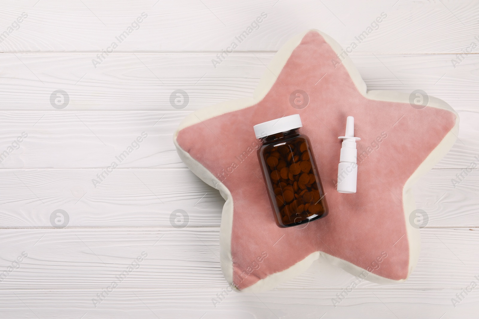 Photo of Pillow, pills and nasal spray on white wooden background, top view. Space for text