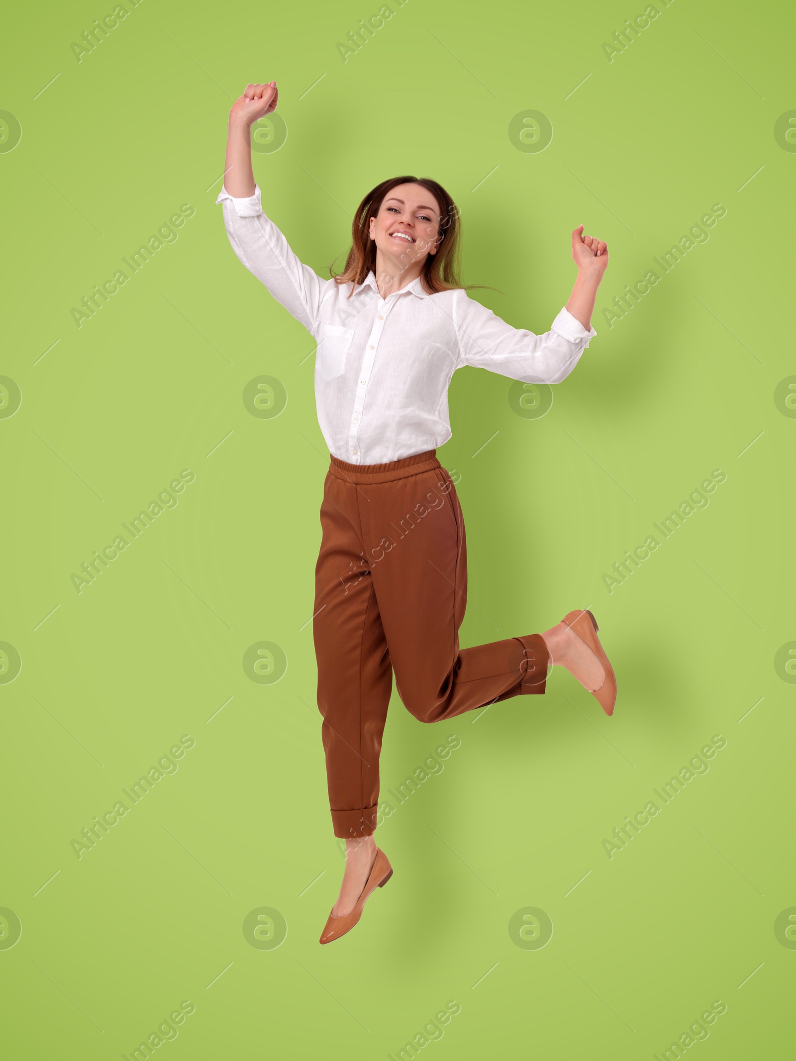 Image of Positive young woman jumping on light green background