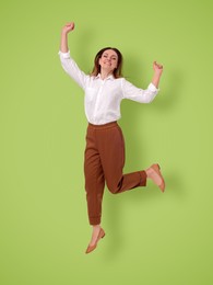 Image of Positive young woman jumping on light green background