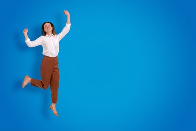 Positive young woman jumping on blue background. Space for text