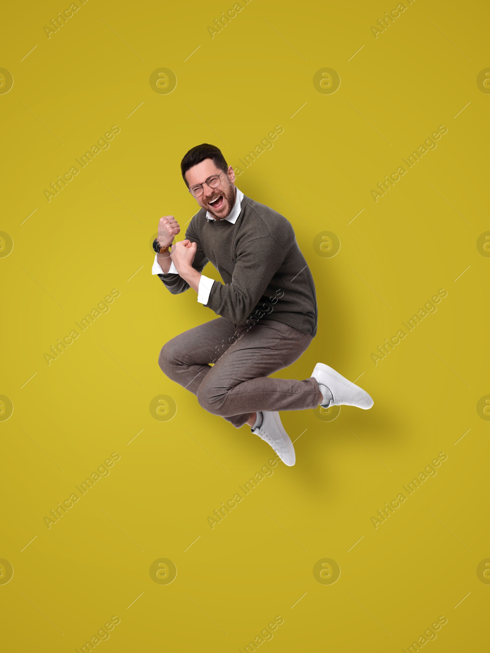 Image of Positive man jumping on olive color background