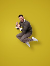 Image of Positive man jumping on olive color background