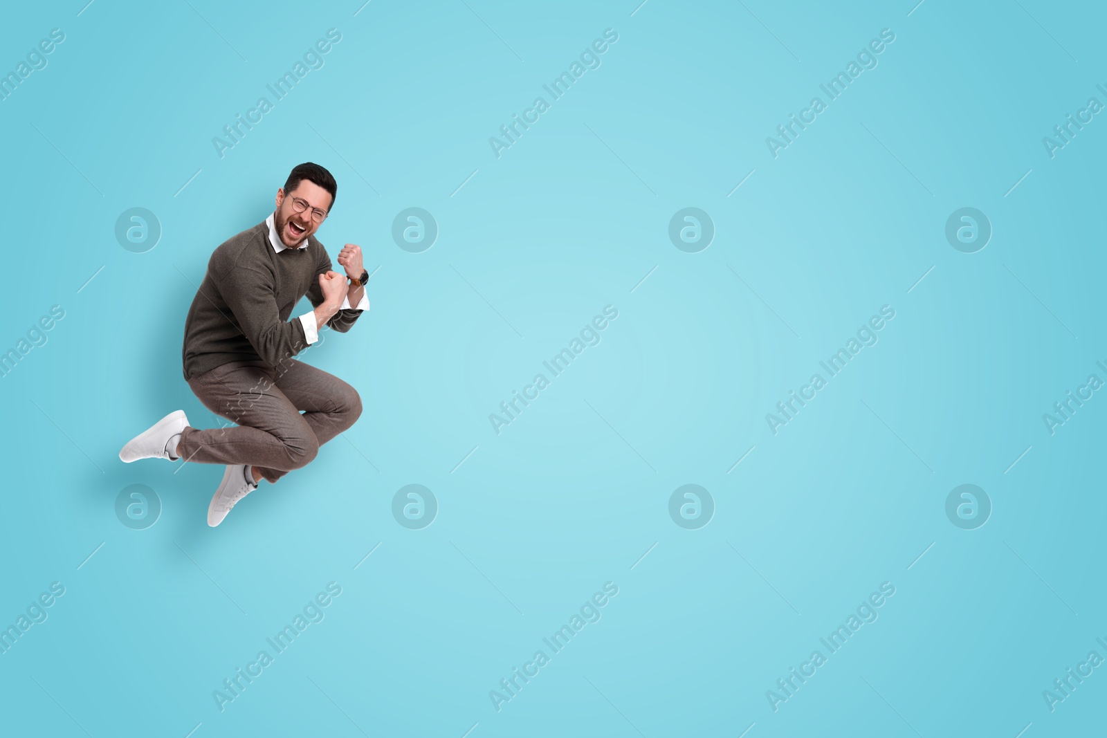 Image of Positive man jumping on light blue background. Space for text