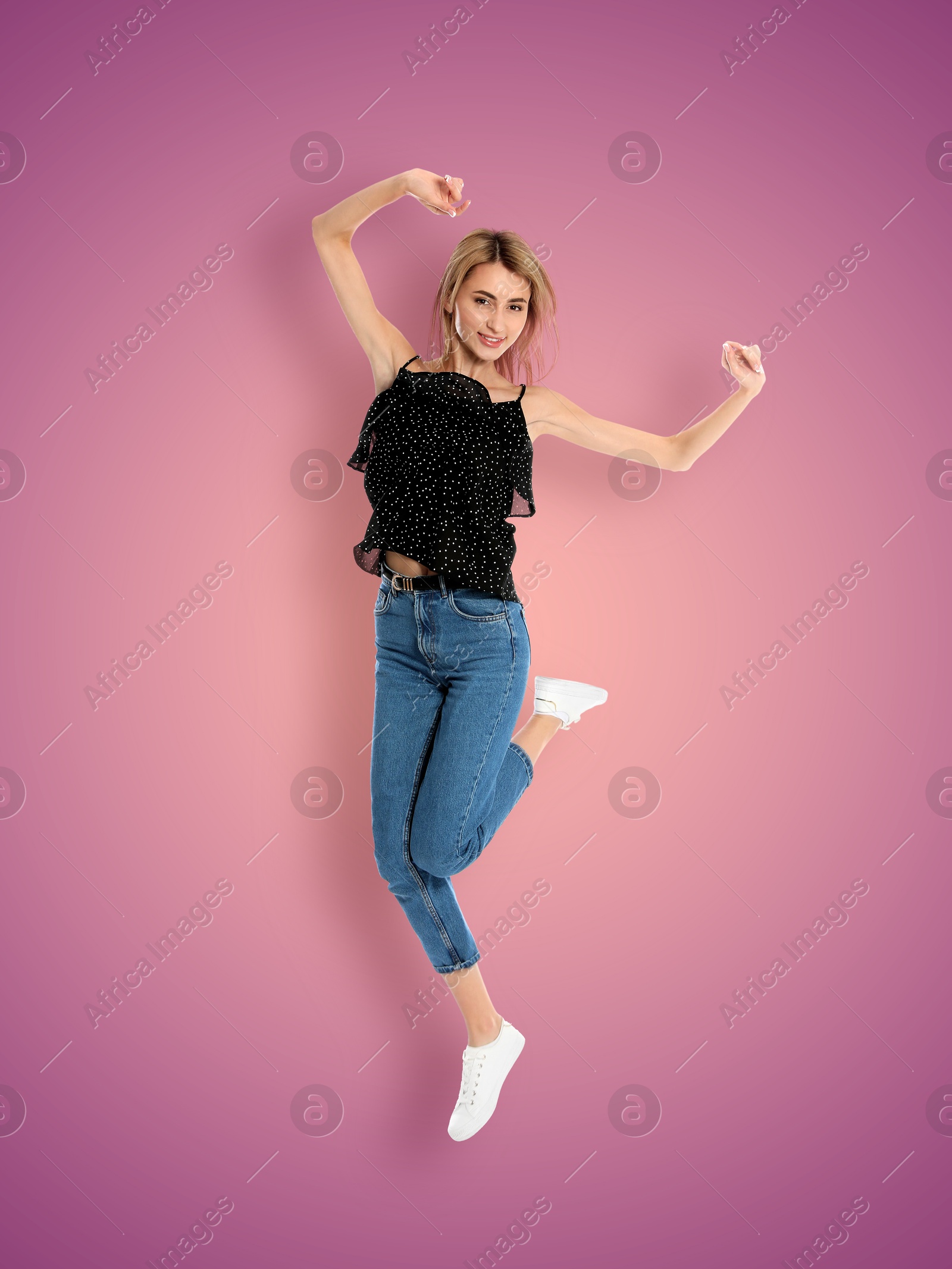 Image of Positive young woman jumping on purple pink gradient background