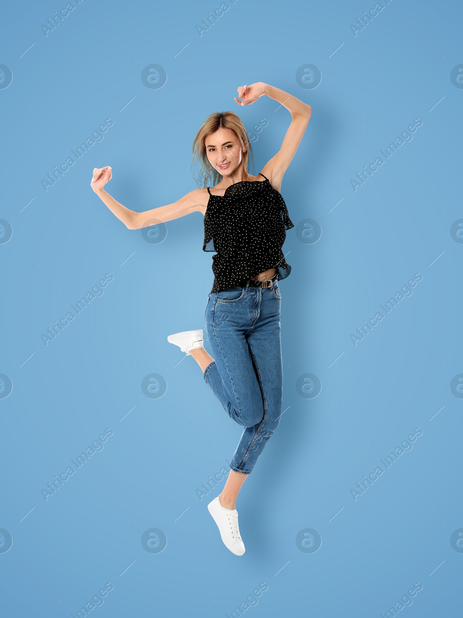 Image of Positive young woman jumping on light blue background