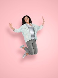 Positive young woman jumping on pink background