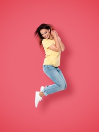 Positive young woman jumping on pink background