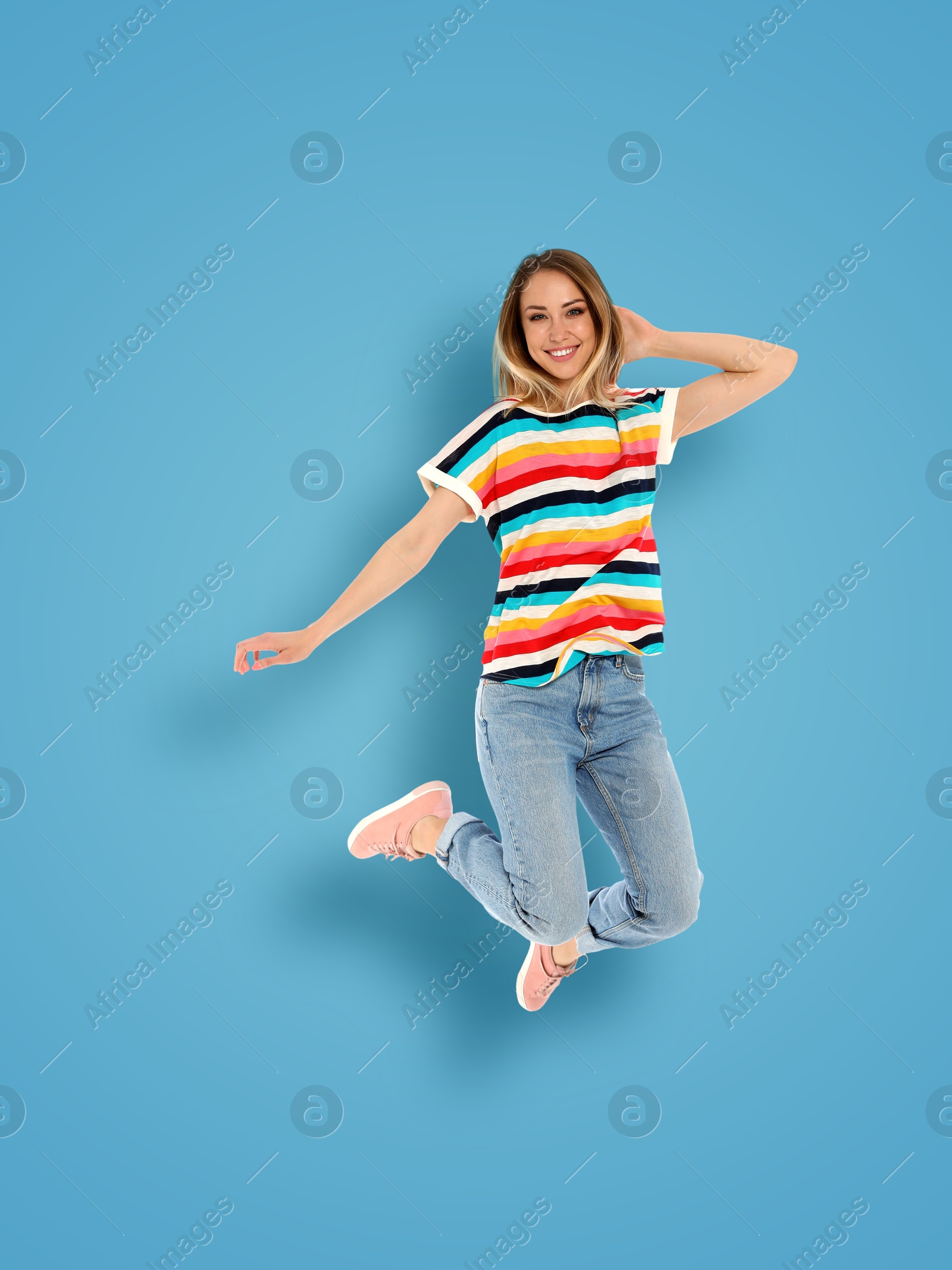 Image of Positive young woman jumping on light blue background