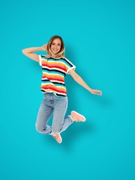 Positive young woman jumping on light blue background