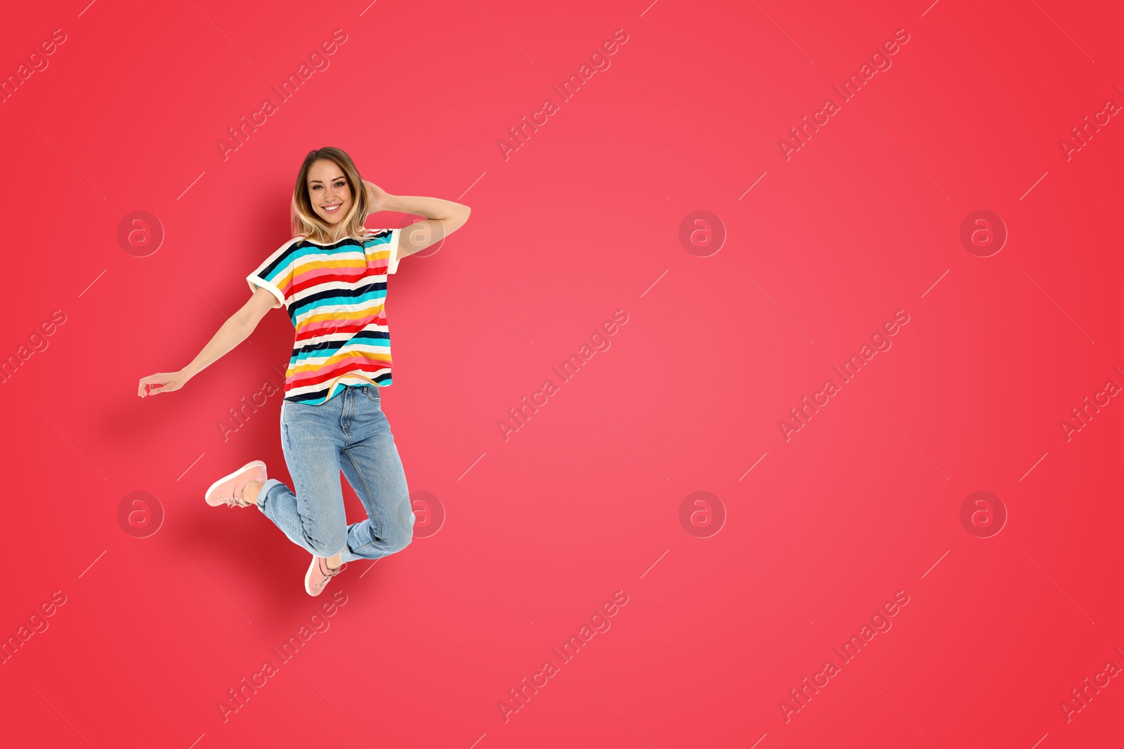 Image of Positive young woman jumping on red background. Space for text