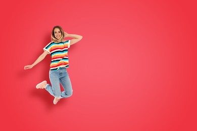 Positive young woman jumping on red background. Space for text