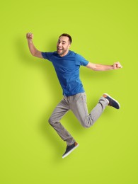 Positive young man jumping on light green background