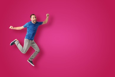 Positive young man jumping on hot pink background. Space for text