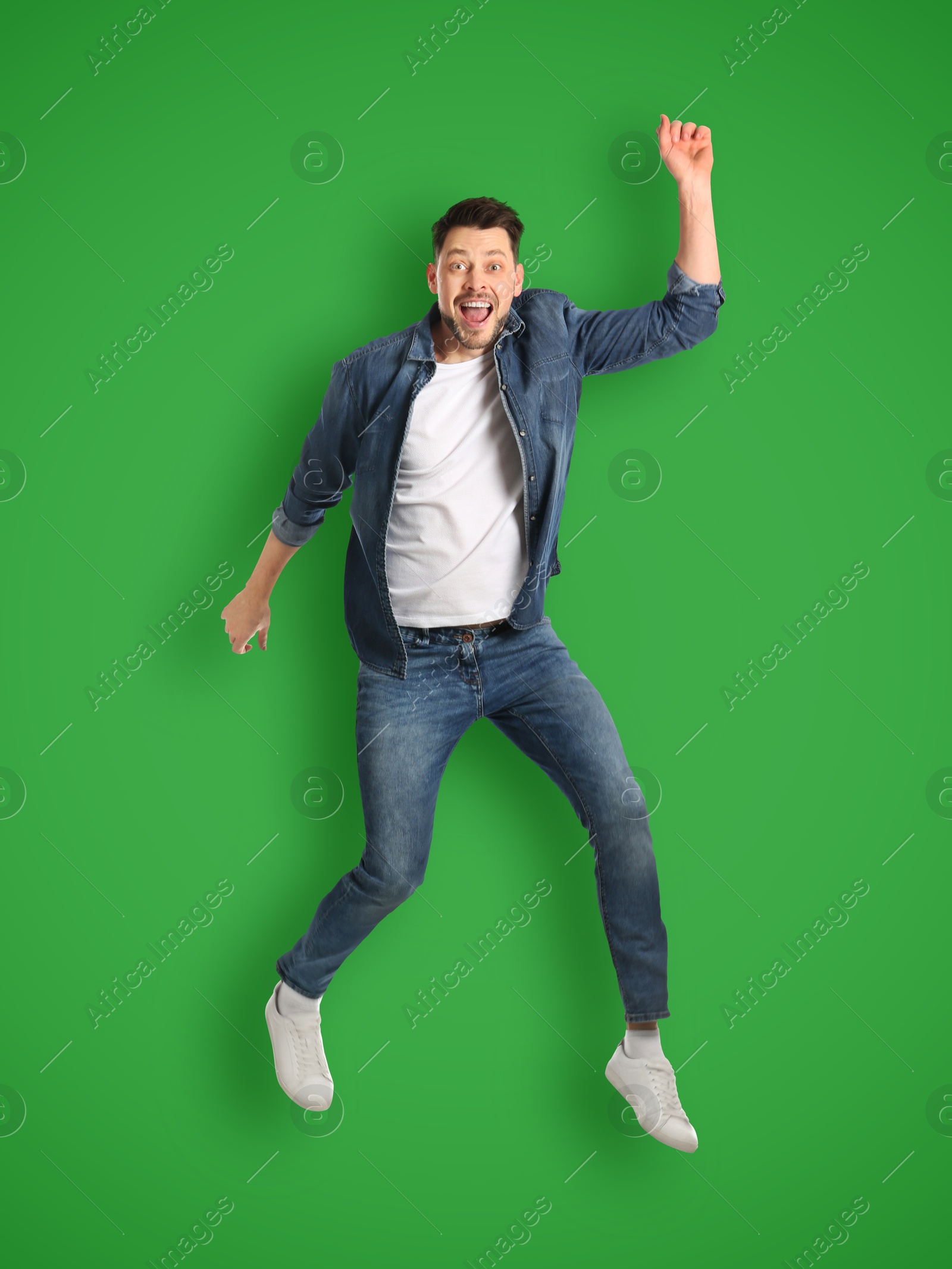 Image of Positive man jumping on bright green background