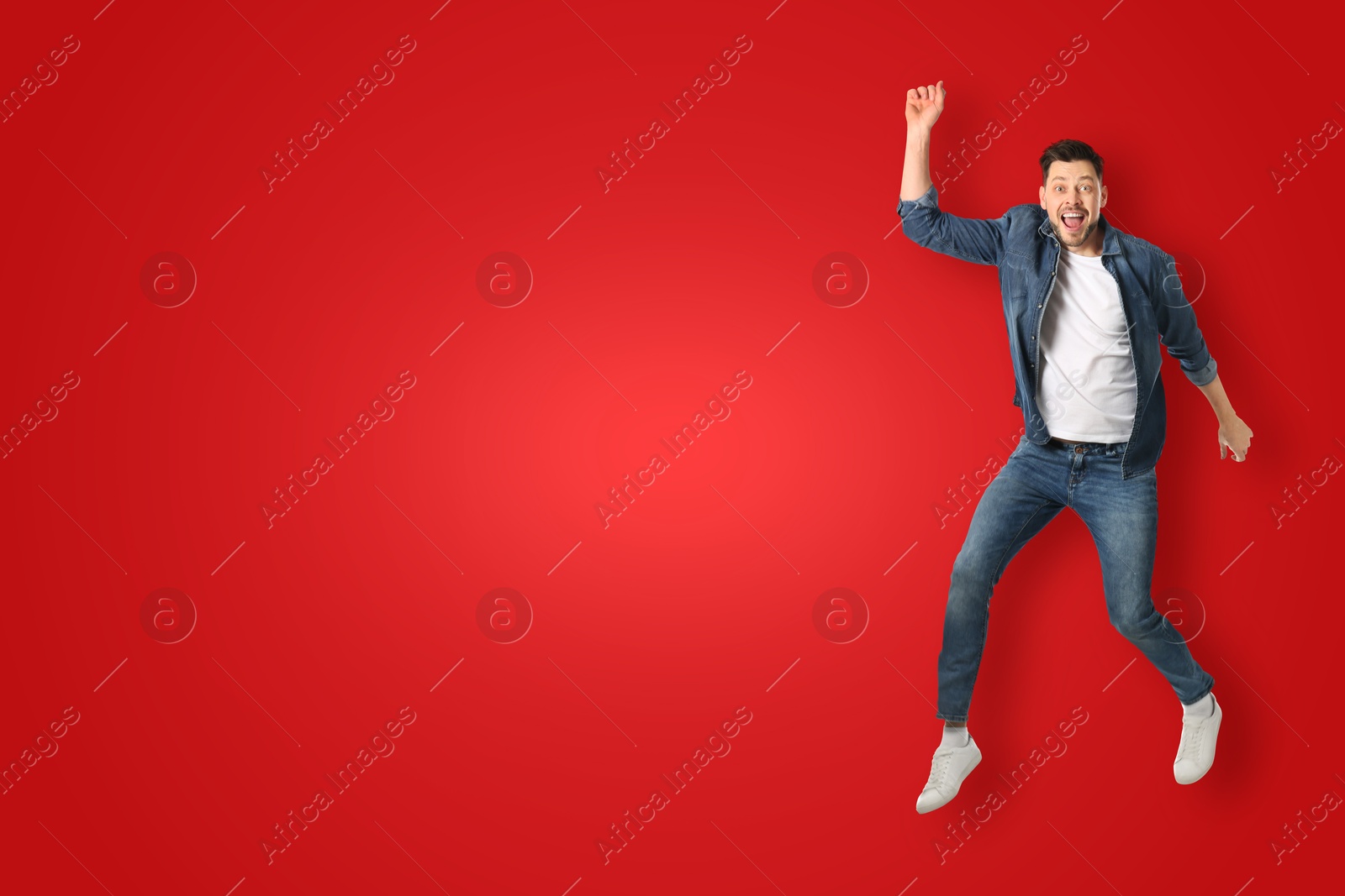 Image of Positive man jumping on red background. Space for text