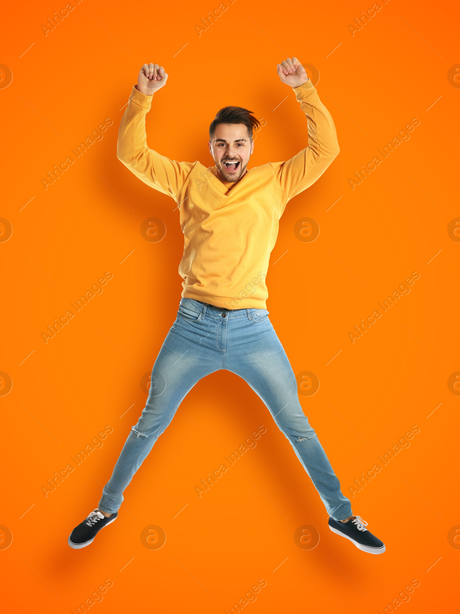 Image of Positive young man jumping on orange background