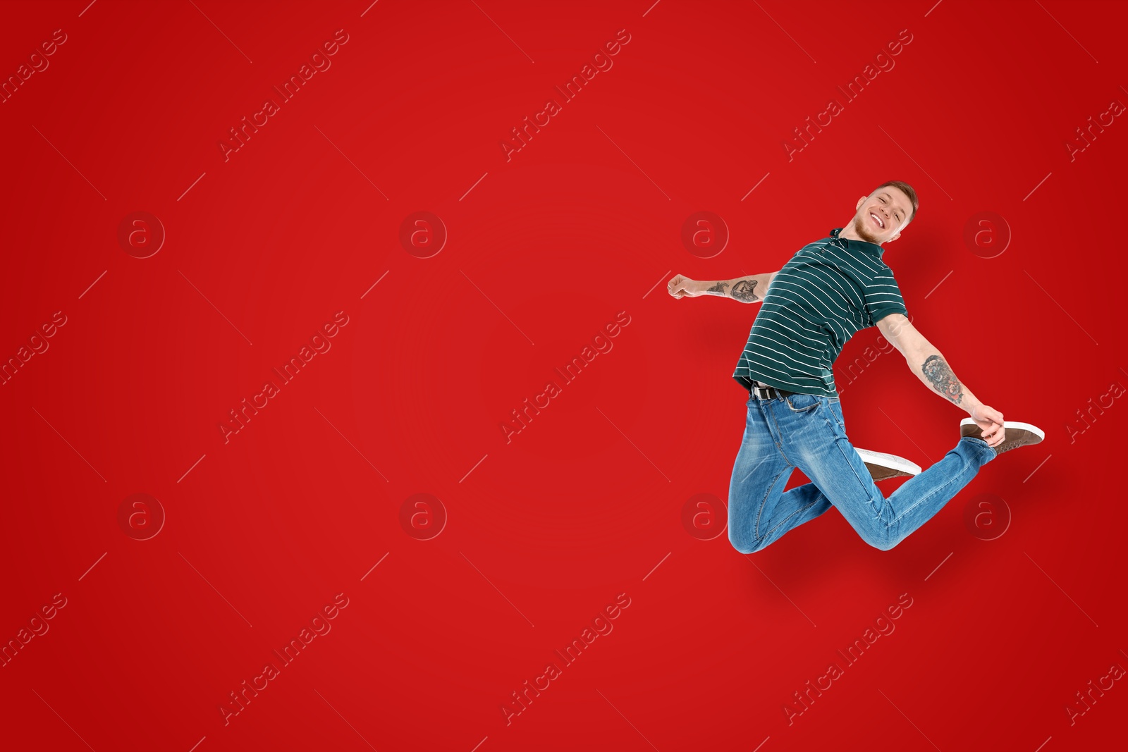 Image of Positive young man jumping on red background. Space for text