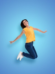 Positive young woman jumping on light blue background