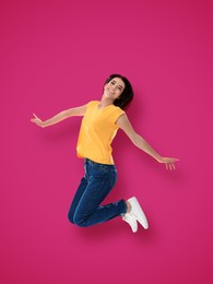 Positive young woman jumping on hot pink background