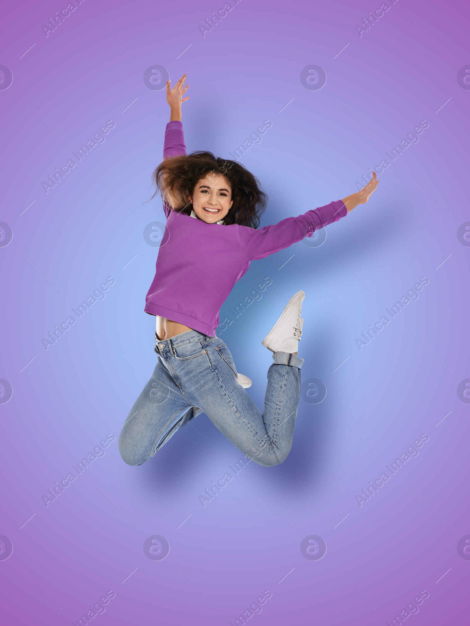 Image of Positive young woman jumping on blue purple gradient background