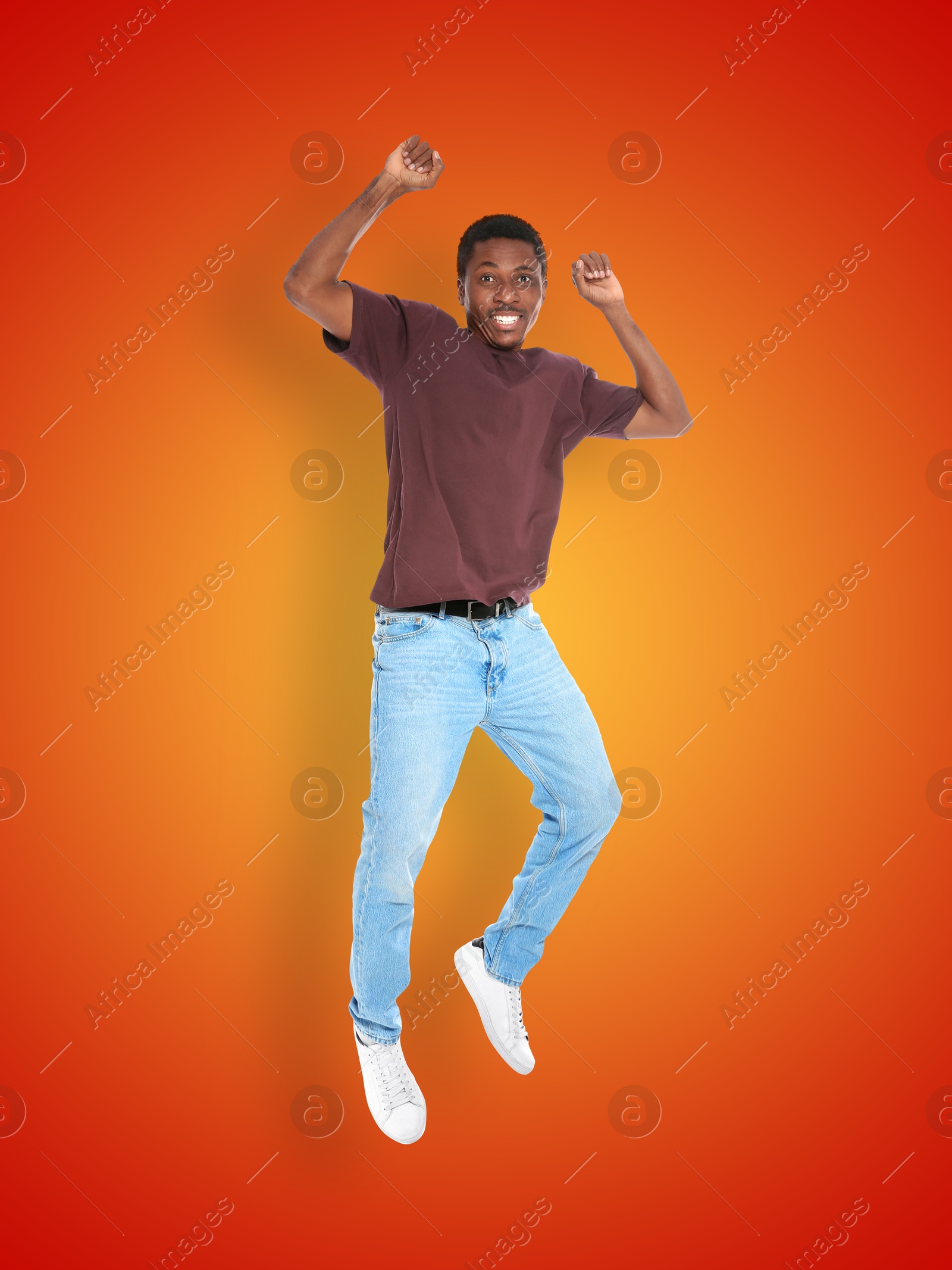 Image of Positive young man jumping on red orange gradient background