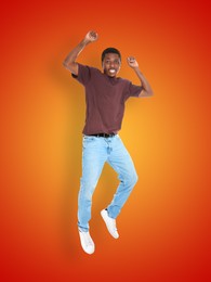 Image of Positive young man jumping on red orange gradient background