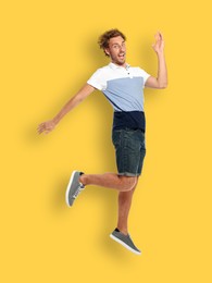 Image of Positive young man jumping on yellow background