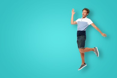 Image of Positive young man jumping on turquoise background. Space for text
