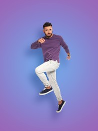 Image of Positive young man jumping on purple gradient background