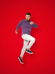Image of Positive young man jumping on red background