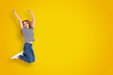 Image of Positive young woman jumping on yellow background. Space for text