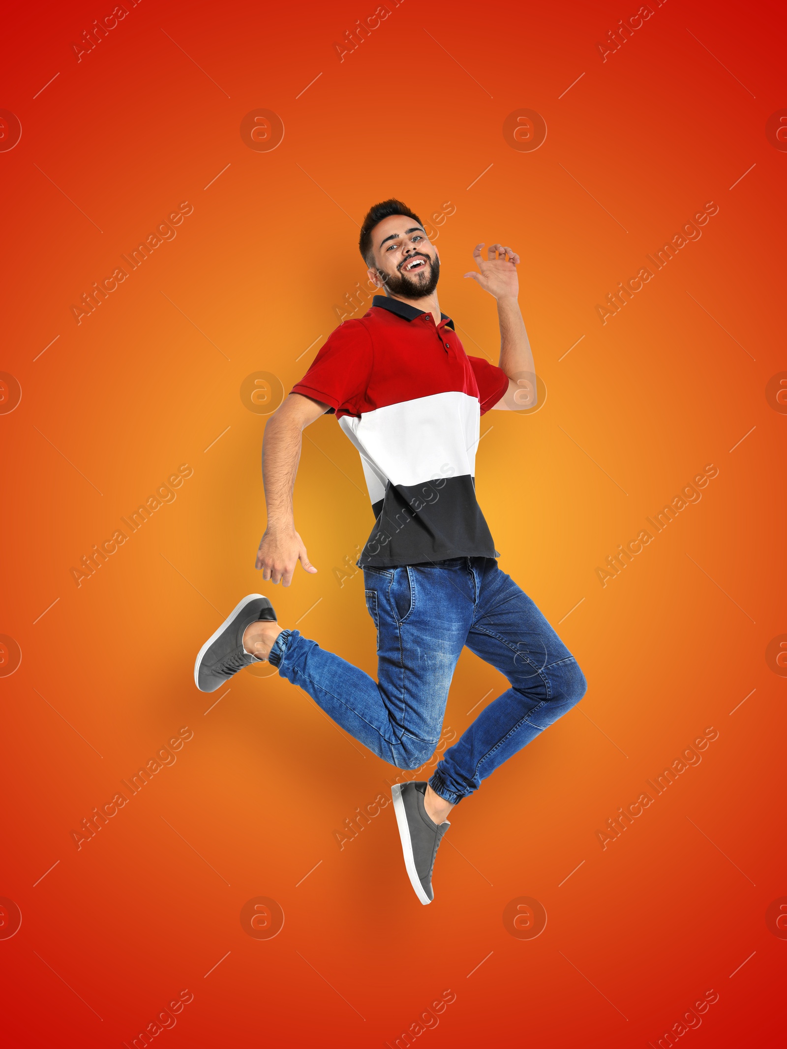 Image of Positive young man jumping on red orange gradient background
