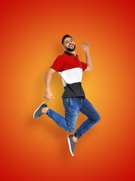 Positive young man jumping on red orange gradient background