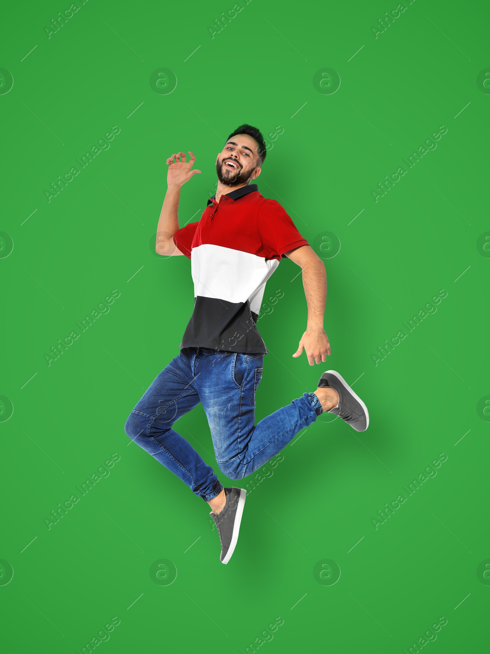 Image of Positive young man jumping on green background