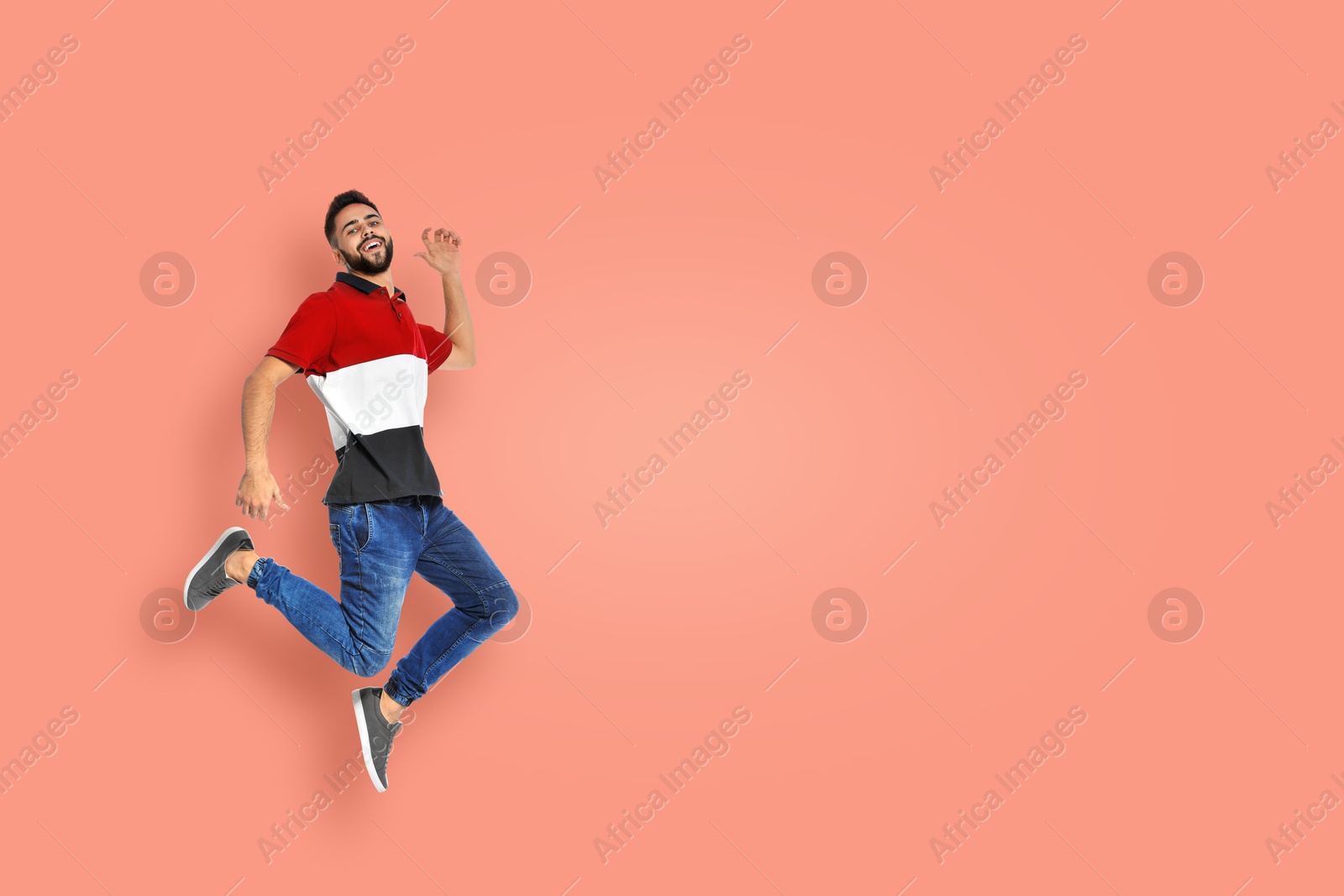 Image of Positive young man jumping on pink background. Space for text