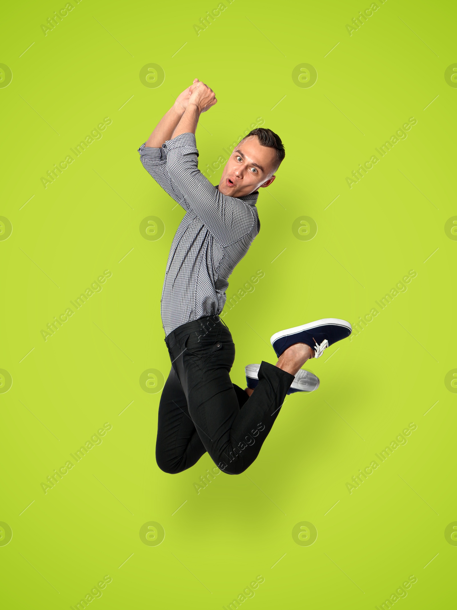 Image of Positive young man jumping on light green background