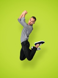 Positive young man jumping on light green background