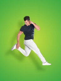 Image of Positive young man jumping on green gradient background