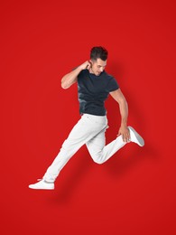 Image of Positive young man jumping on red background