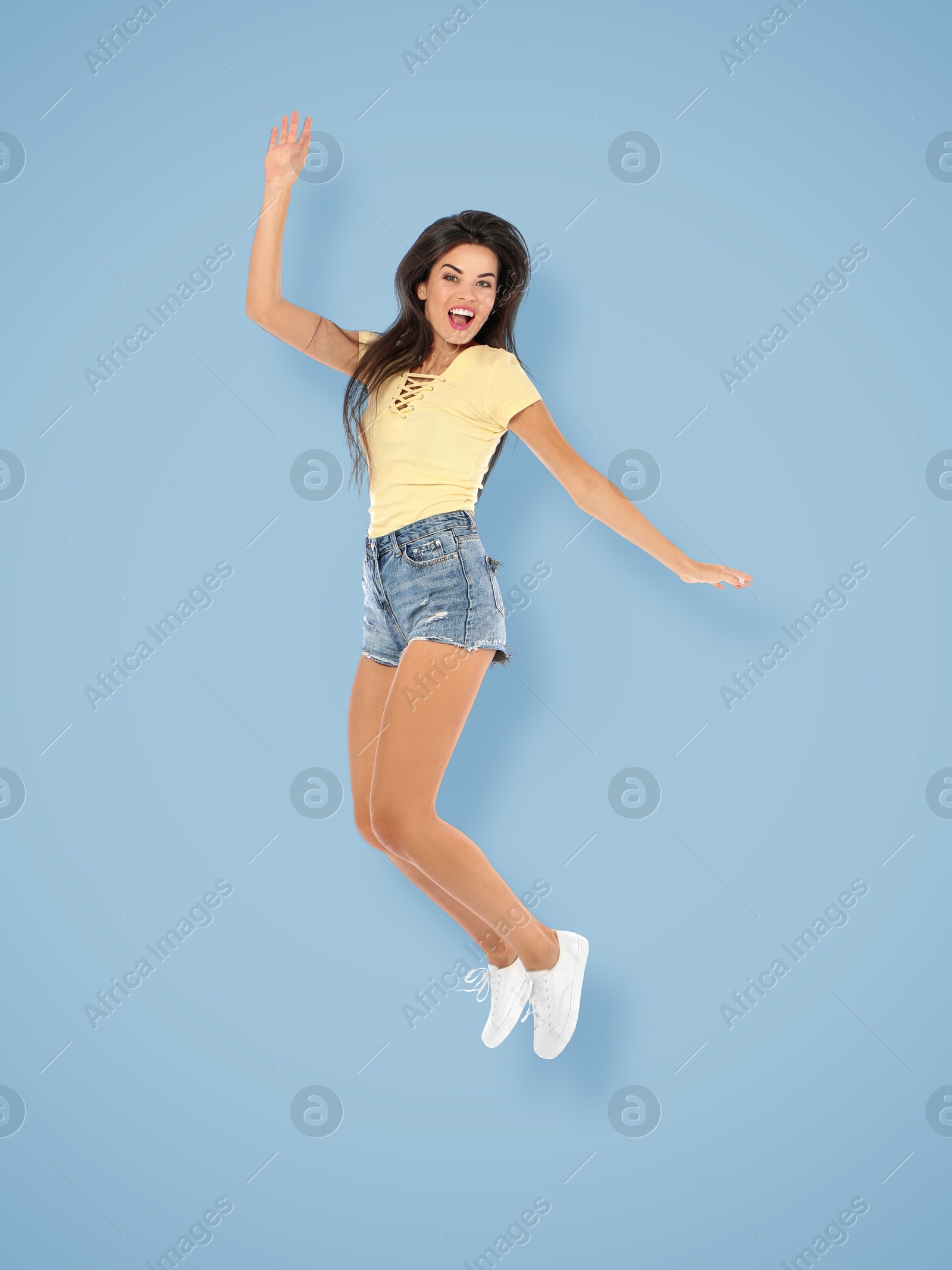 Image of Positive young woman jumping on light blue background