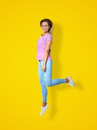 Image of Positive young woman jumping on yellow background