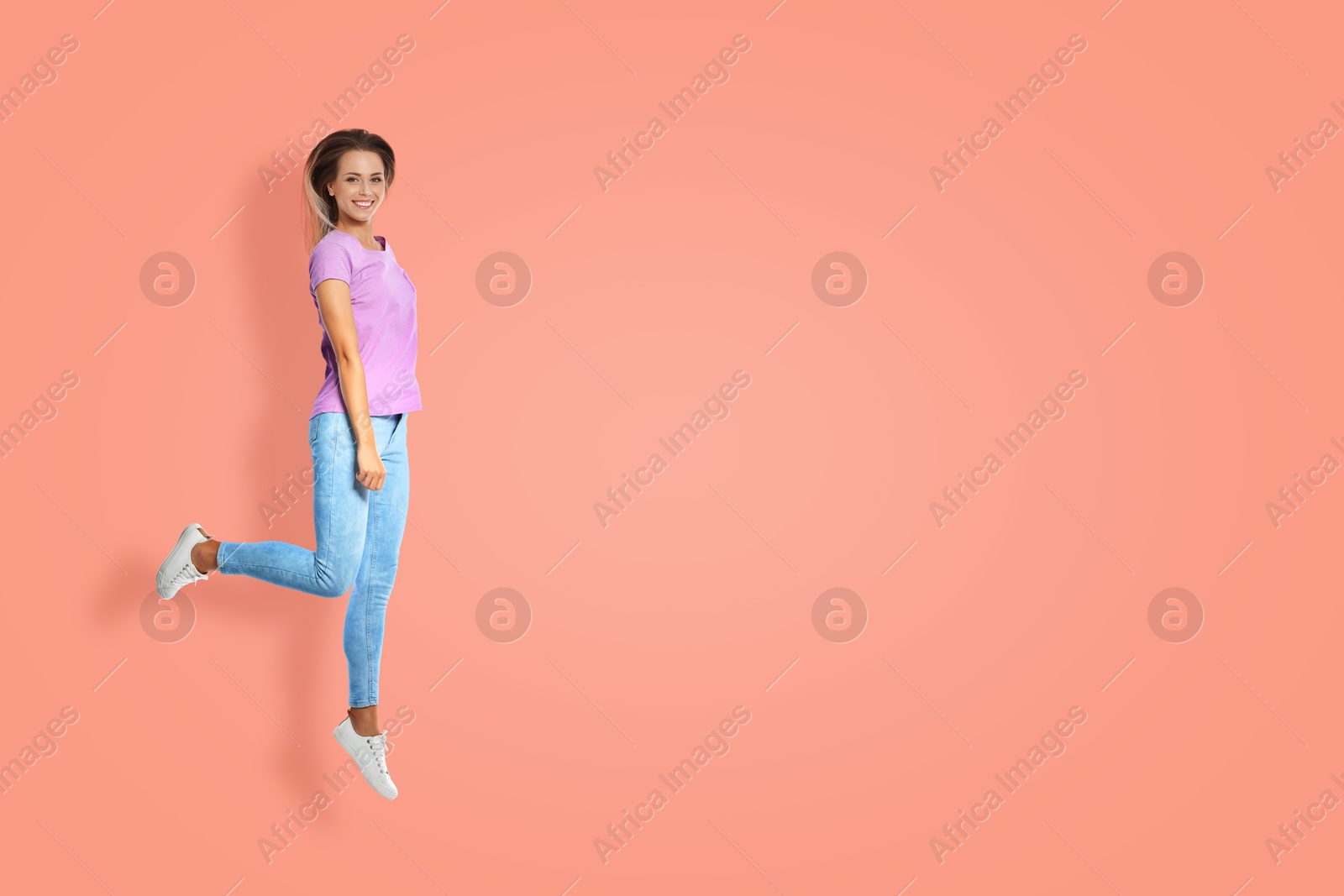 Image of Positive young woman jumping on pink background. Space for text