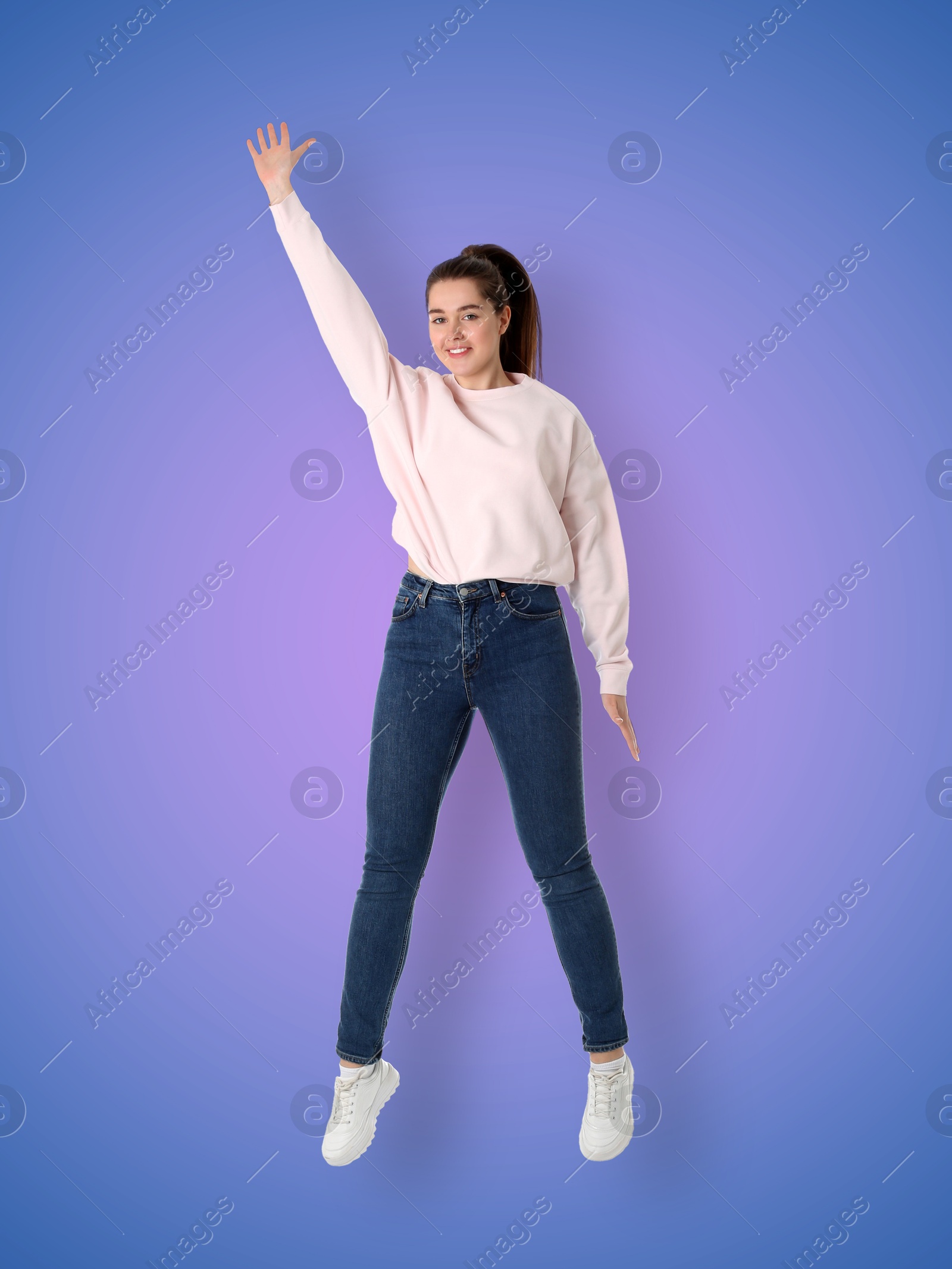 Image of Positive young woman jumping on purple blue gradient background