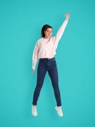 Positive young woman jumping on light blue background