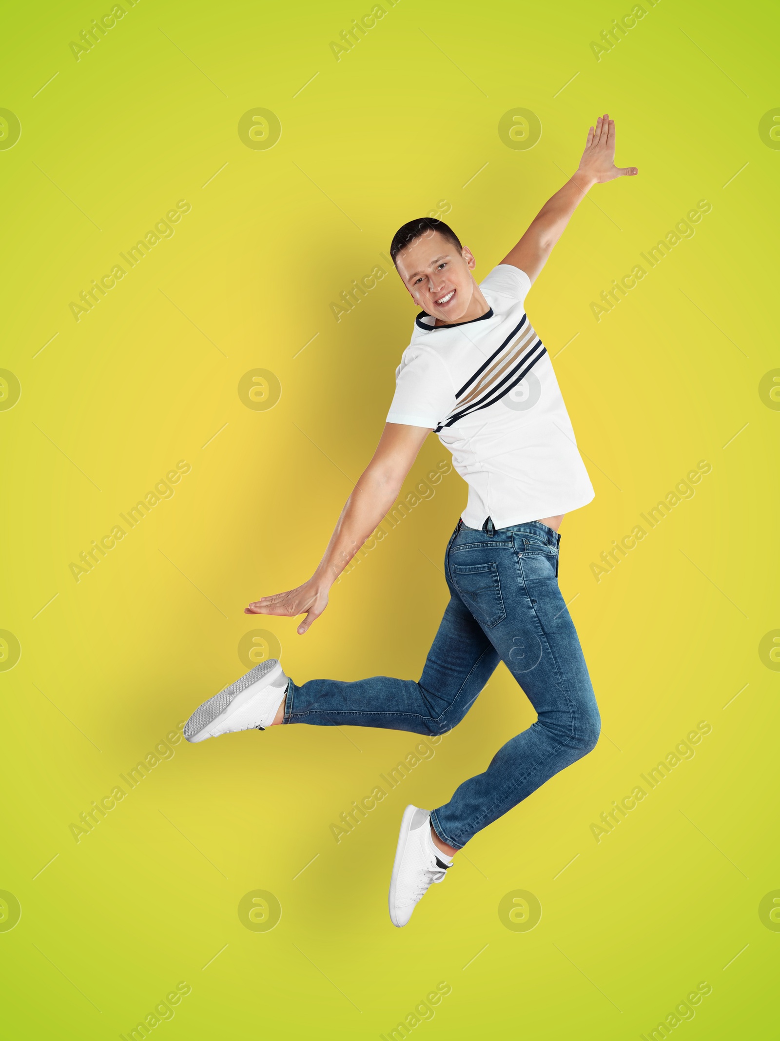 Image of Positive young man jumping on yellow green gradient background