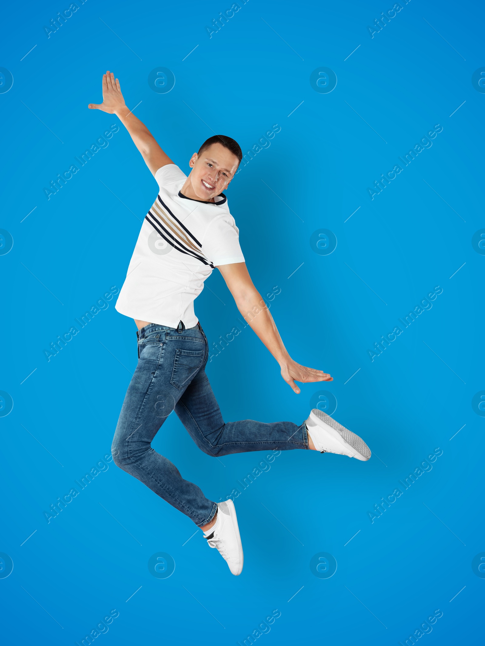 Image of Positive young man jumping on blue background