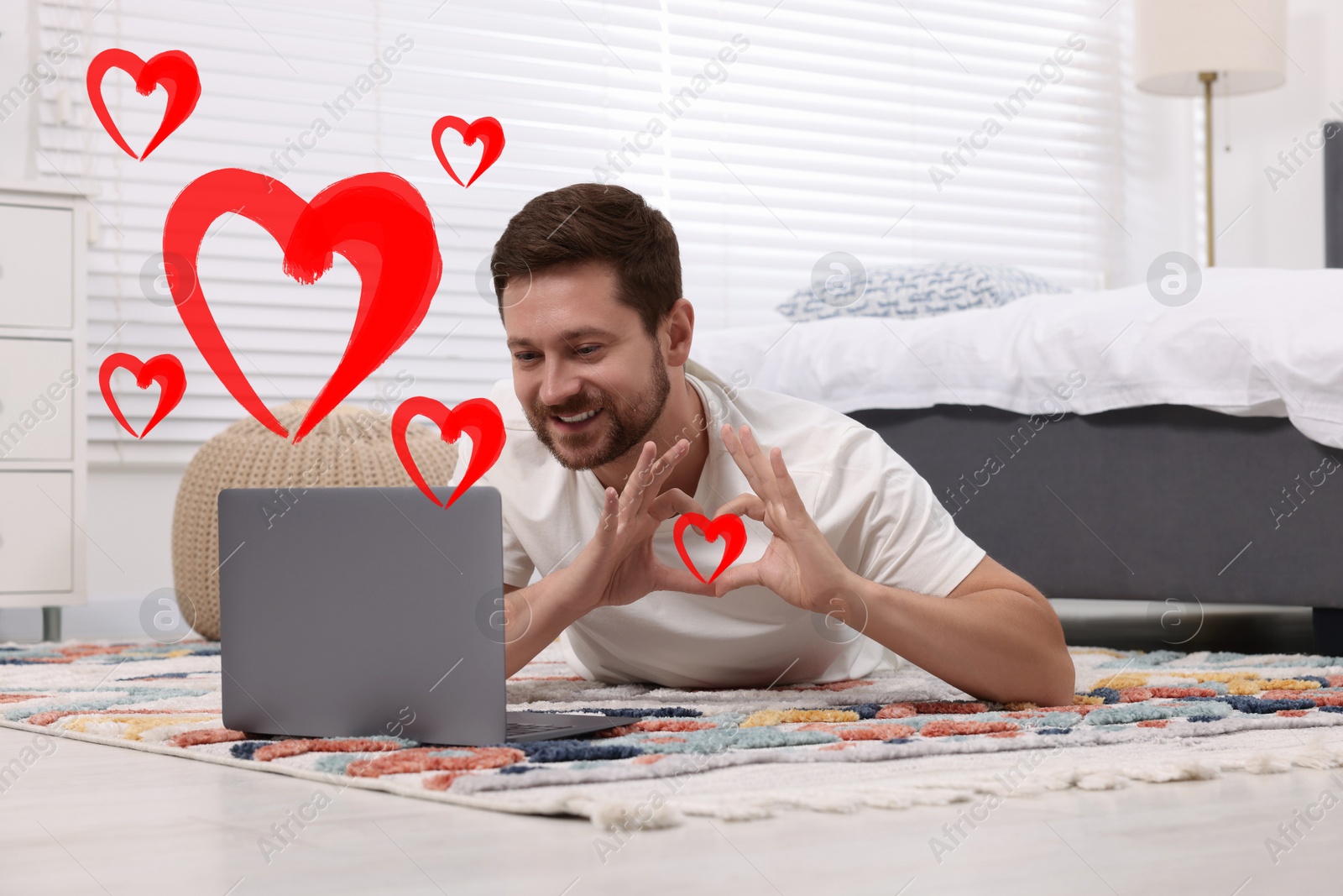 Image of Long distance relationship. Man having video chat with his loved one indoors. Red hearts near him