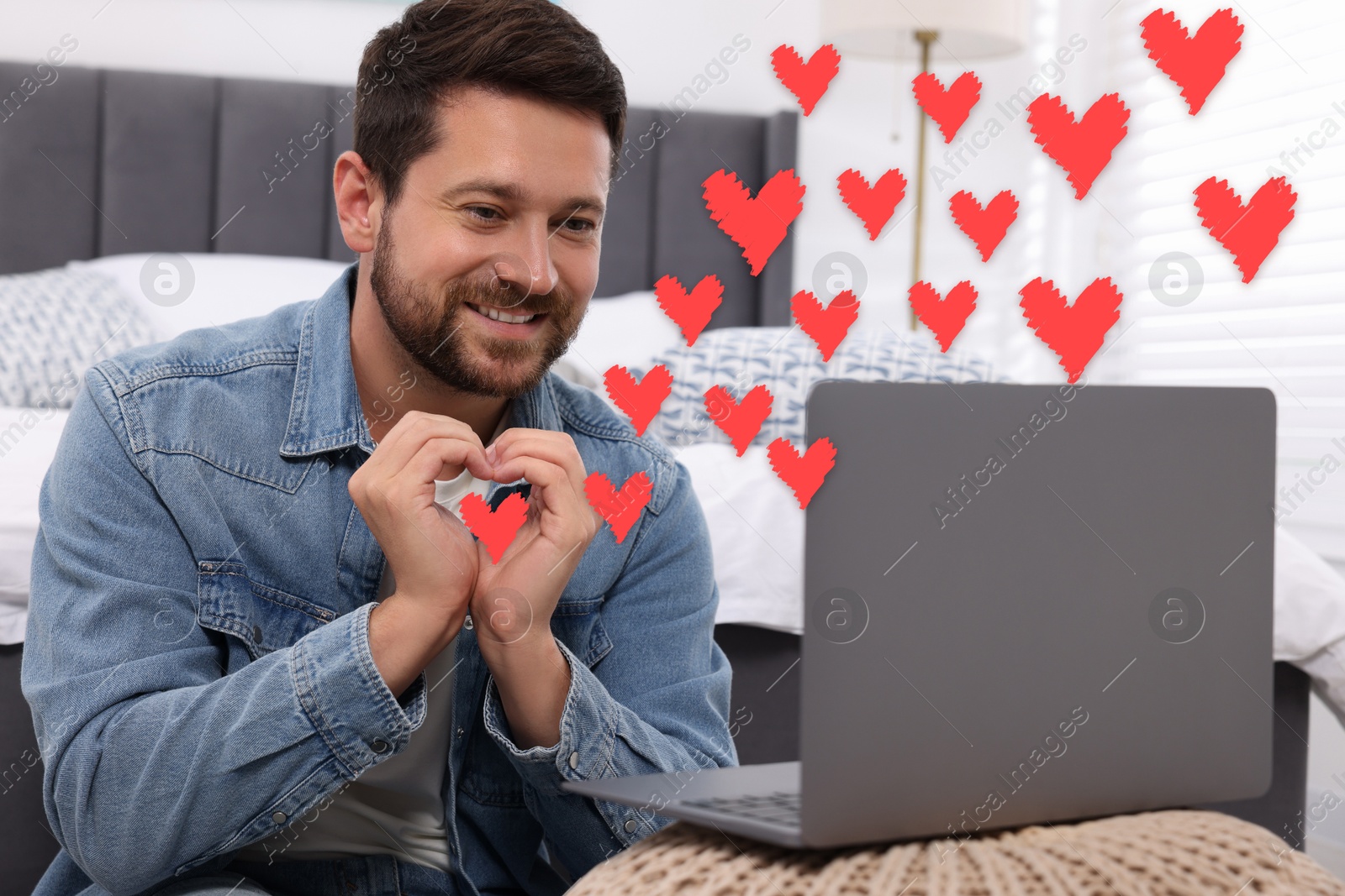 Image of Long distance relationship. Man having video chat with his loved one indoors. Red hearts near him